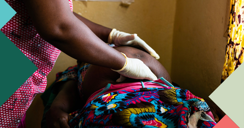 A health visitor wearing latex gloves checks the belly of a pregnant women as part of her routine pre-natal care.